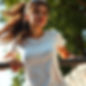 A woman in a t-shirt, just finished her run, leaning on a bar. The camera shot is from bel