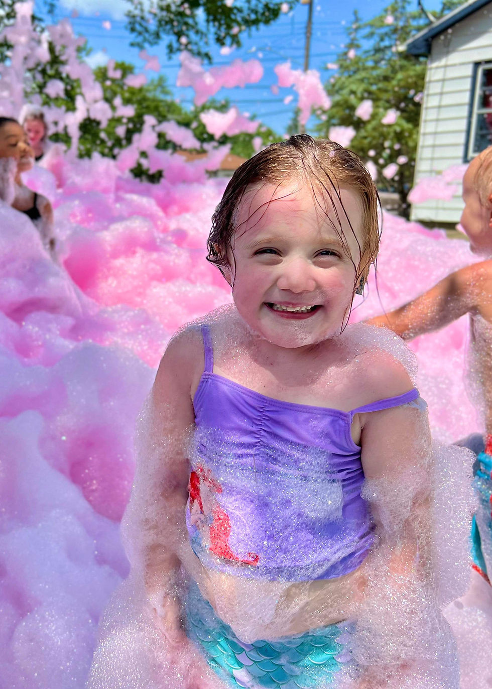 kid smiling in a sea of neon pink foam
