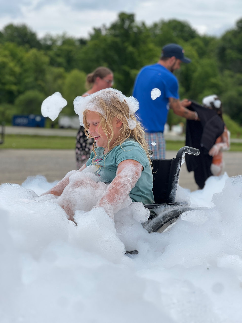 a giggling girl in a wheelchair glides through a vast sea foam