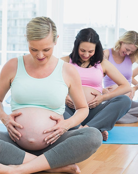 Pregnant women sitting on mats touching