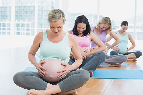 Pregnant women sitting on mats touching 