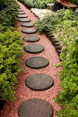 A neat path of circular stones and red gravel. modern garden design