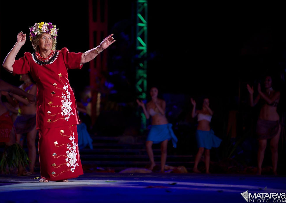 Photo of a Polynesian queen dancing on stage with flowers and a red dress