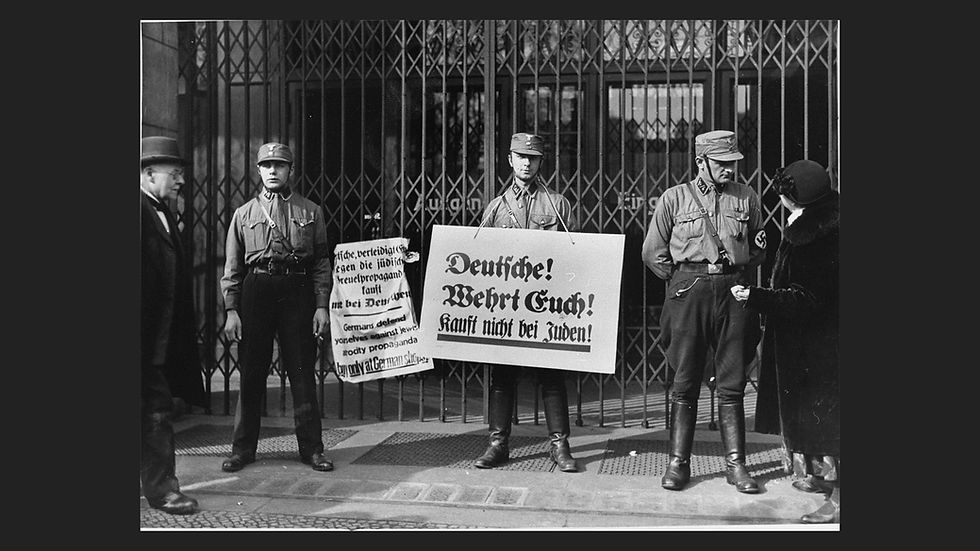 Black-and-white photo of uniformed SA men with boycott signs at the entrance of a Jewish-owned shop in Berlin, April 1, 1933.