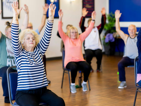A group of mature adullts doing low-impact chair exercises