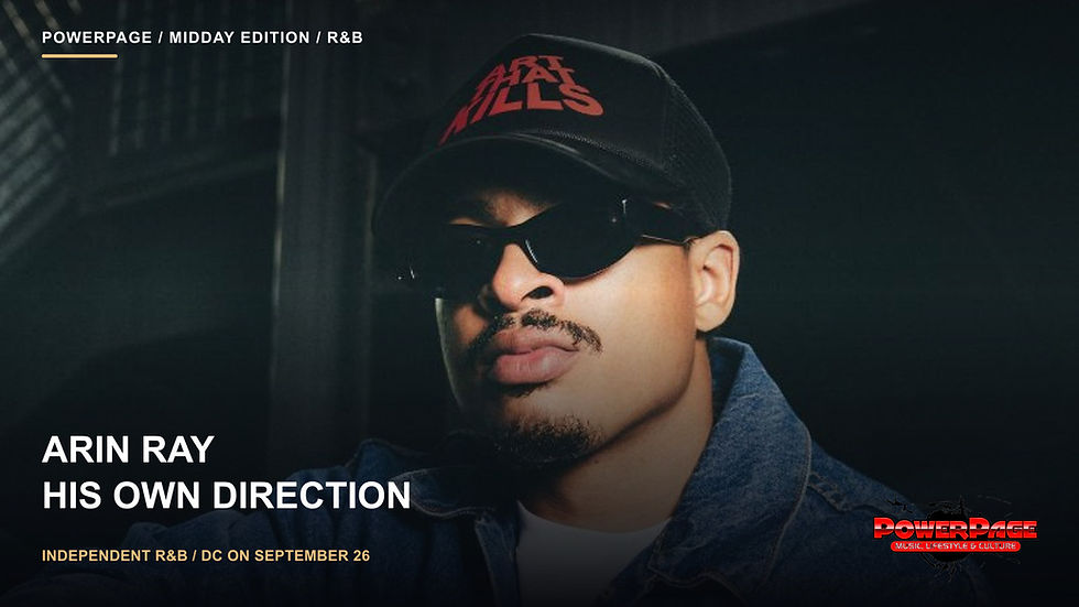 Arin Ray in sunglasses, a black cap with red lettering and a denim jacket against a dark background.