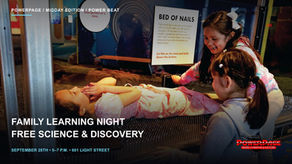 Three children interact with the Maryland Science Center’s Bed of Nails exhibit, with one child lying on the exhibit and two beside it.