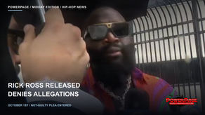 Rick Ross, wearing sunglasses and a brightly colored shirt, faces microphones outside a fenced entrance.