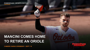 Trey Mancini raises his Orioles batting helmet while standing on the field at Camden Yards