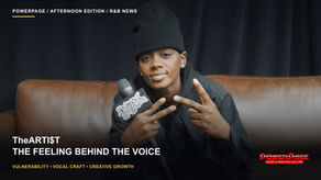 TheARTI$T sits on a brown couch holding an interview microphone.