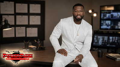 50 Cent seated in a white suit inside a television development office in a PowerPage editorial image.
