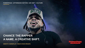 Chance the Rapper smiles beneath a baseball cap, with stage lights and haze behind him.