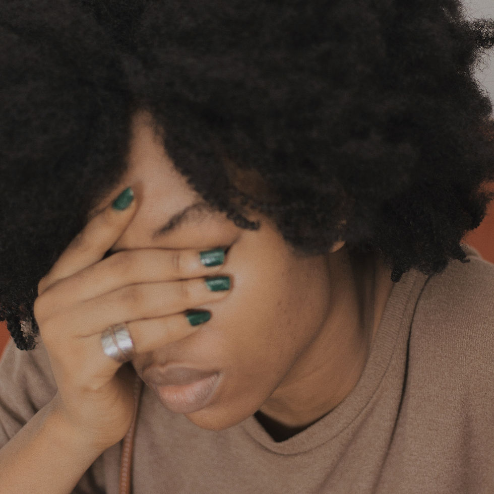 African American woman covering her face with her hand looking sad.