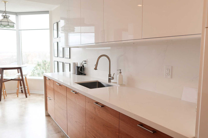 Minimalist kitchen with white quartz countertop and natural wood lower cabinets