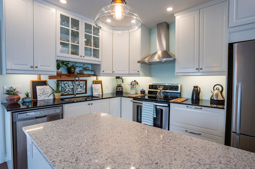 Speckled quartz kitchen island with white shaker cabinets and black perimeter countertops