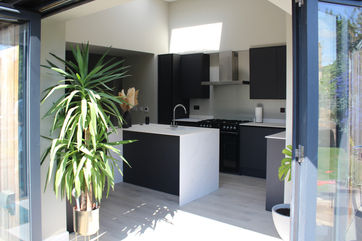 Wide shot of the kitchen viewed through the large patio doors - emphasising the new multifunctional space provided by a bespoke kitchen refurbishment.