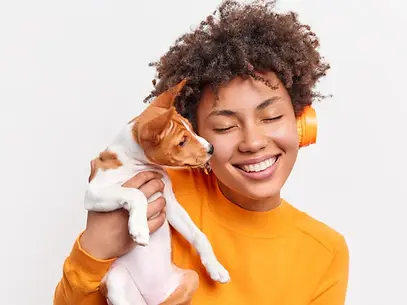 eine_junge_frau_mit_lockigem_haar_und_orangefarbenen_kopfhorern_lachelt_mit_geschlossenen_