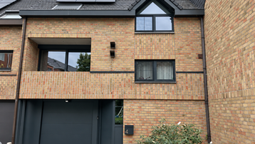 Haus mit dunklen Aluminiumfenstern, -türen und Garagentor