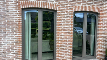 Graue Reynaers-Aluminiumfenster mit falschem Bogen in Backsteinfassade
