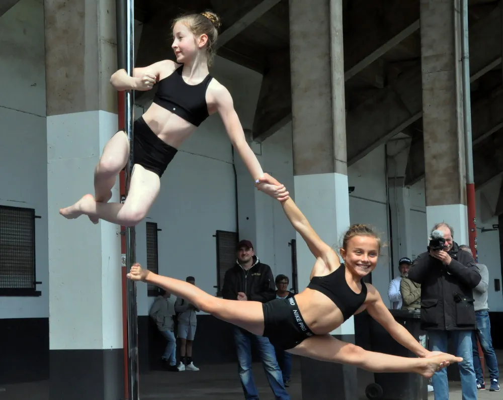 Maria und Alyssa performing a beautiful pole dance double trick with a split 