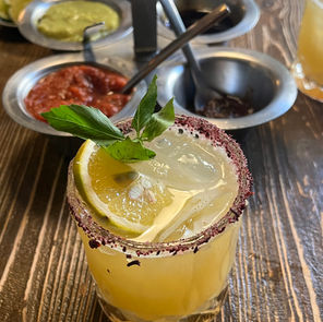 Margarita in a tahini rimmed glass with salsas