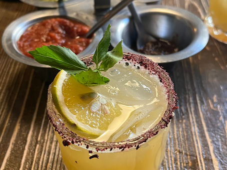 Margarita in a tahini rimmed glass with salsas