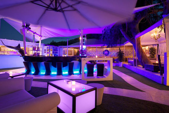 Verlichte bar met zitplaatsen en parasol. Apex Events met een blauwe gloed.