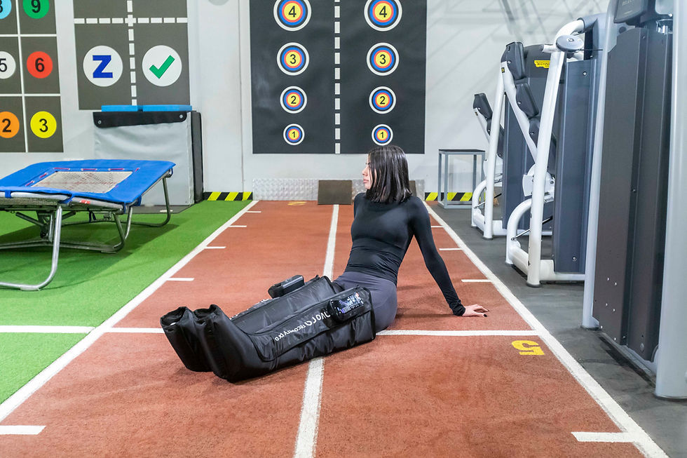 Athlete using Avora Recovery Pro air-compression leg recovery boots on a gym track—post-workout compression therapy.