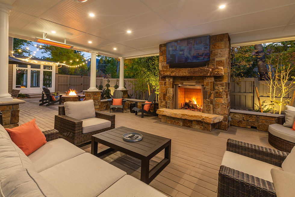 Stone outdoor fireplace and fire pit on a covered patio at dusk