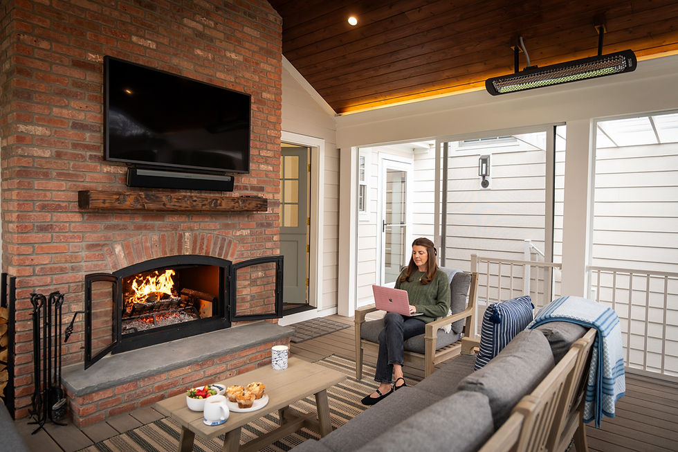 Wood burning brick fireplace on a covered porch with a woman relaxing nearby