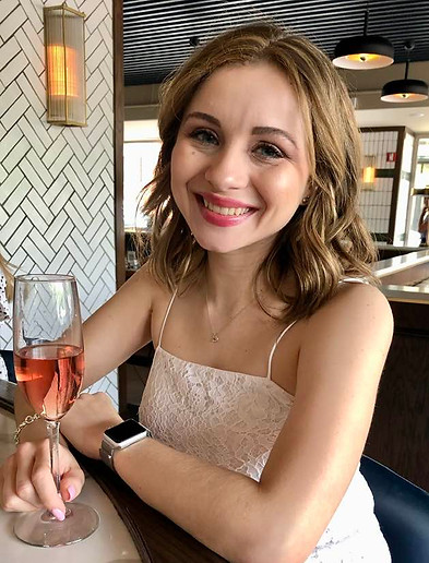 Mia in a white dress with a glass of pink champagne