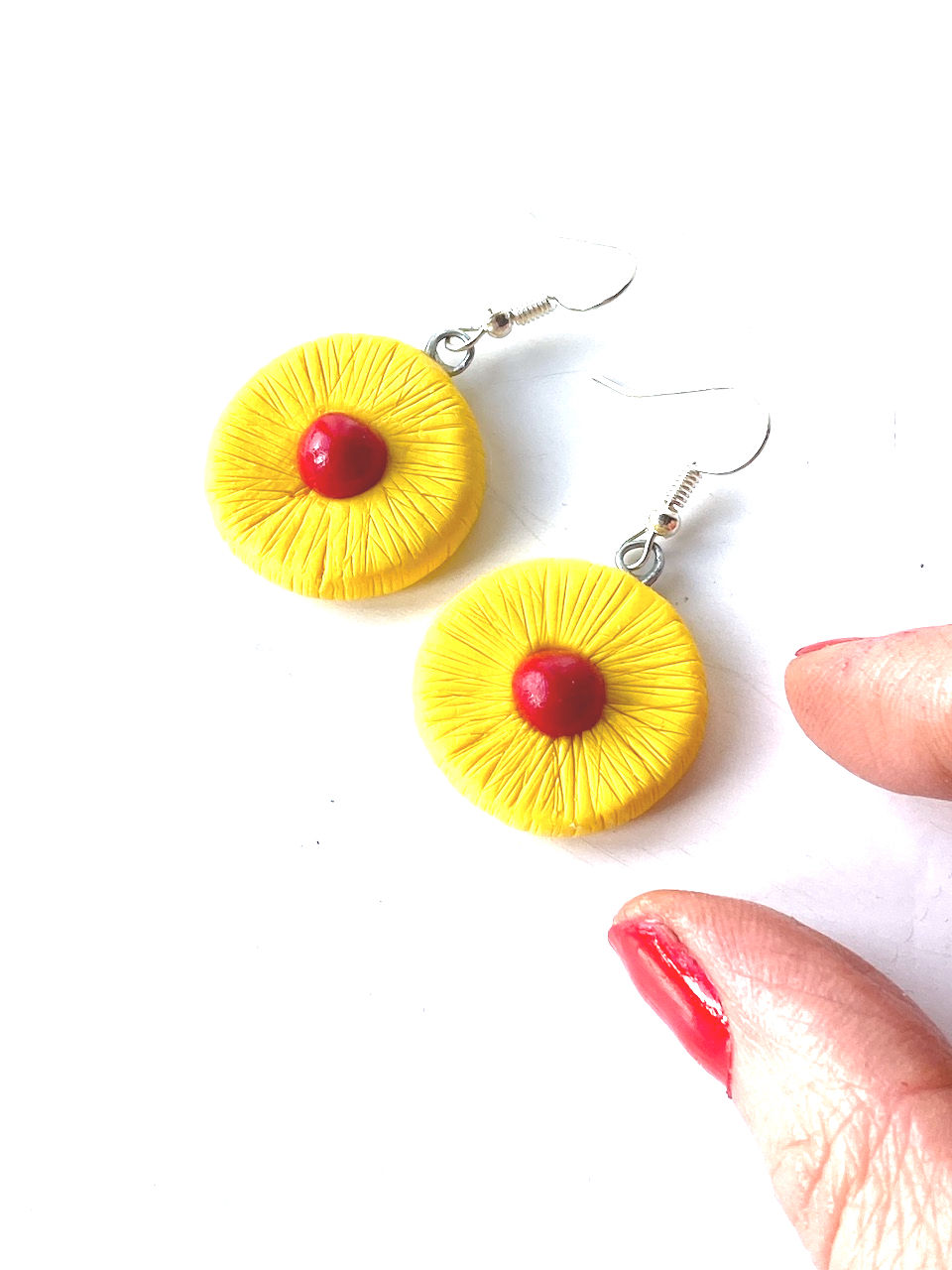 Thumbnail: main avec boucles d'oreilles tranches d'ananas cerise
