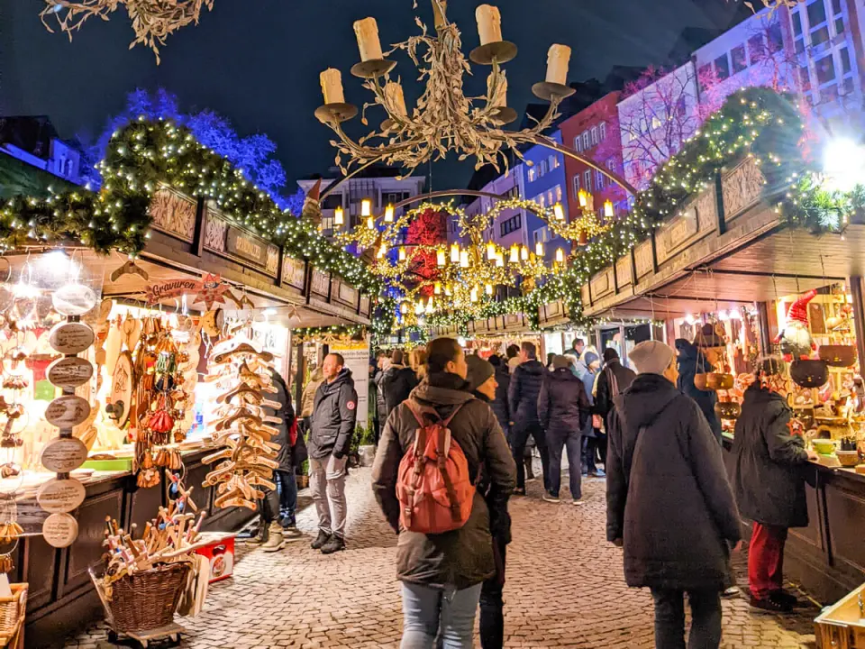 View of a bustling German Christmas market with twinkling lights and festive stalls