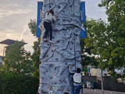 Two children scaling the Mendip Climbing Tower with harnesses on, silhouetted against a golden sunset sky.