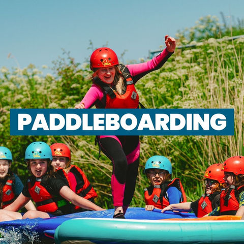 Group of schoolchildren paddleboarding together during a school activity day trip in Somerset.