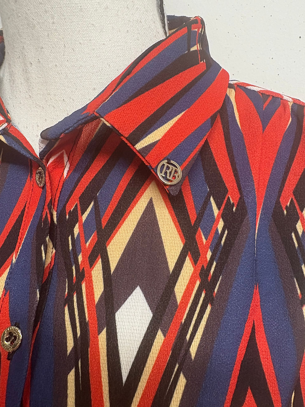 Colorful collared shirt with geometric patterns and button detail closeup