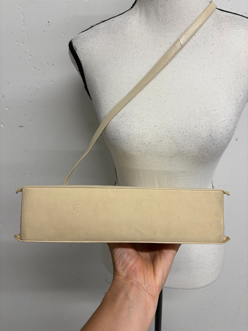 Miniaturbild: Beige Handtasche auf einem Schaufensterpuppen-Oberkörper, Nahaufnahme, Detailansicht.