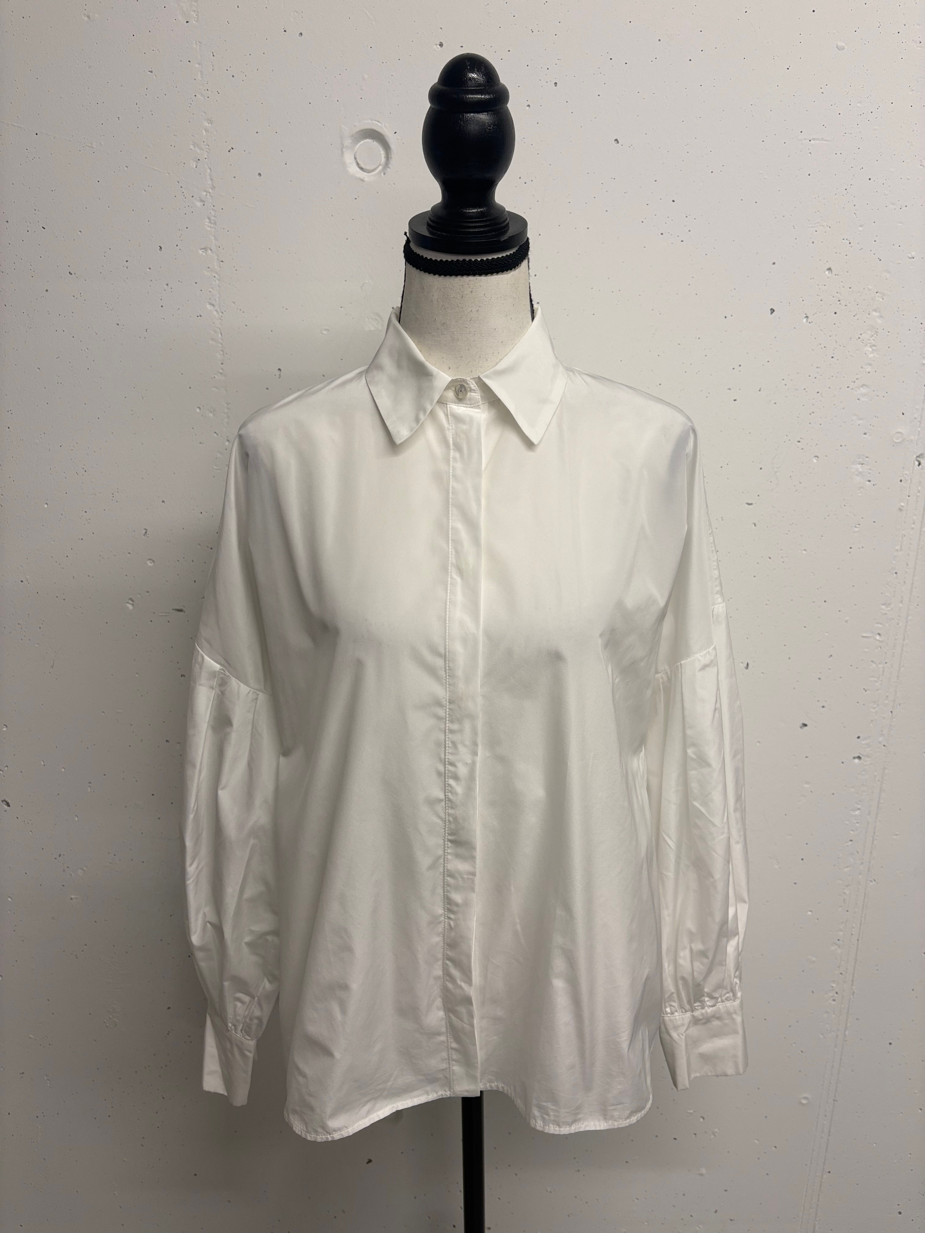 Weiße Bluse auf einer Büste, vor weißem Hintergrund. Schlichtes Design.