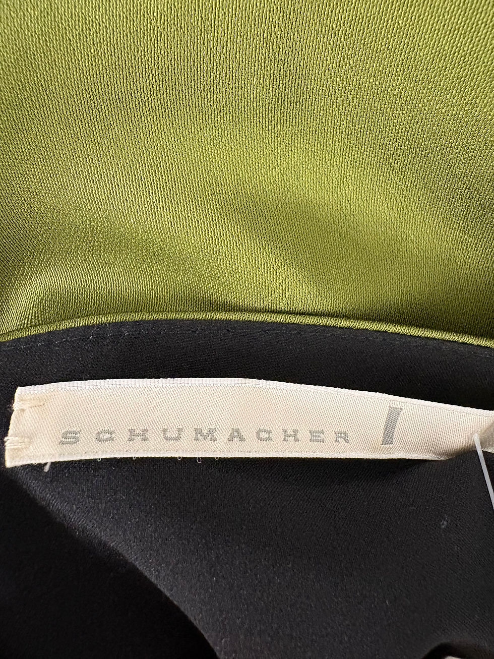 Miniaturbild: Nahaufnahme eines SCHUMACHER-Etiketts auf einem Kleidungsstück mit grünem Hintergrund.