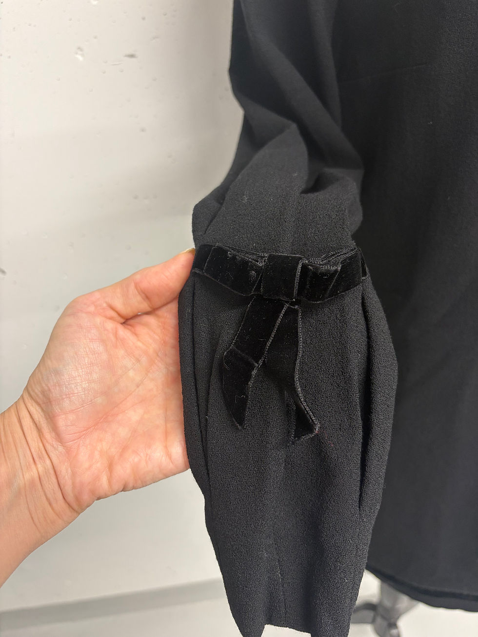 Miniaturbild: Schwarzer Ärmel mit Samtschleife, Detailaufnahme einer Hand, Vintage-Kleidung, Modeaccessoire