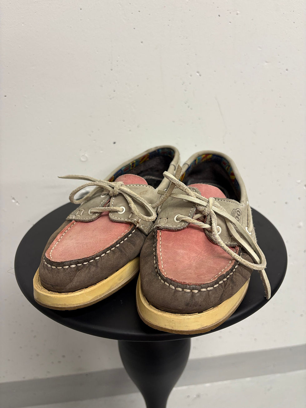 Paar bunte Segelschuhe auf einem schwarzen Tisch im Studio, Nahaufnahme.