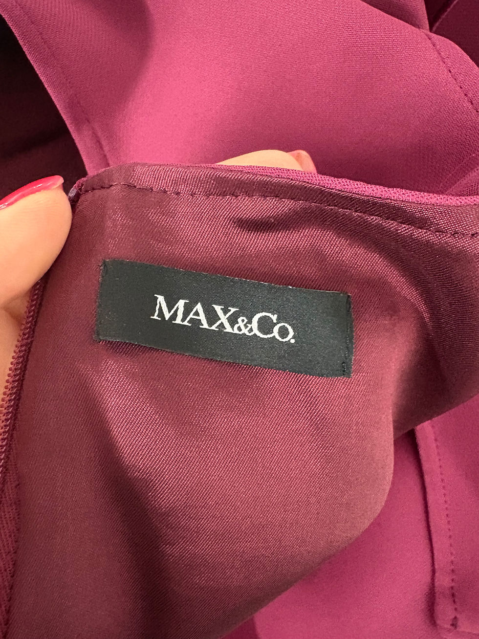 Miniaturbild: Nahaufnahme des Etiketts mit der Aufschrift MAX&Co. auf einem Kleidungsstück
