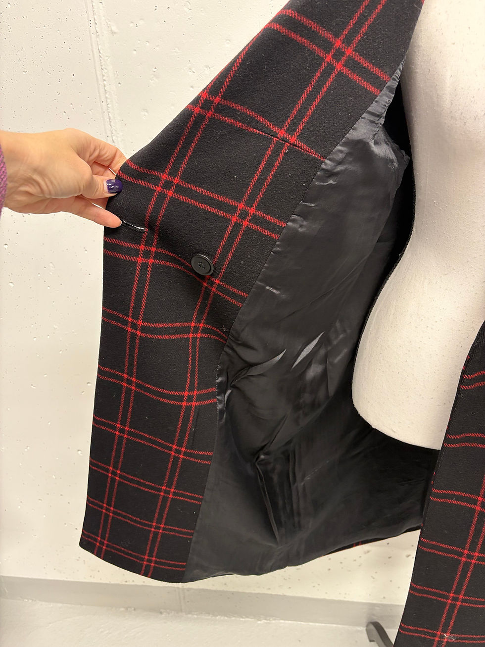 Miniaturbild: Schwarzer karierter Blazer, rote Linien, die Hand zeigt das Innenfutter, nahaufnahme, Mode.