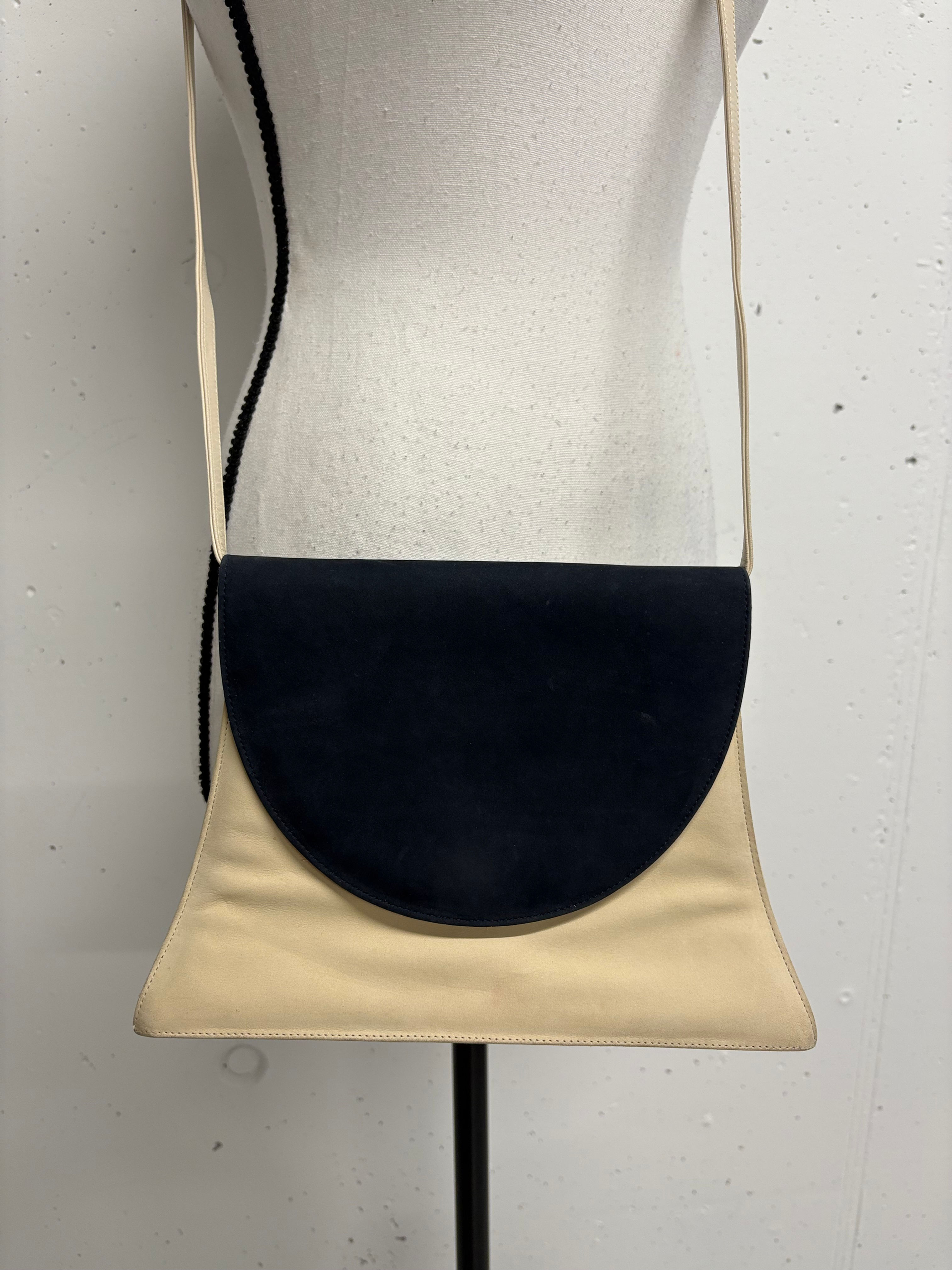 Elegant crossbody bag with black top and beige bottom on a mannequin