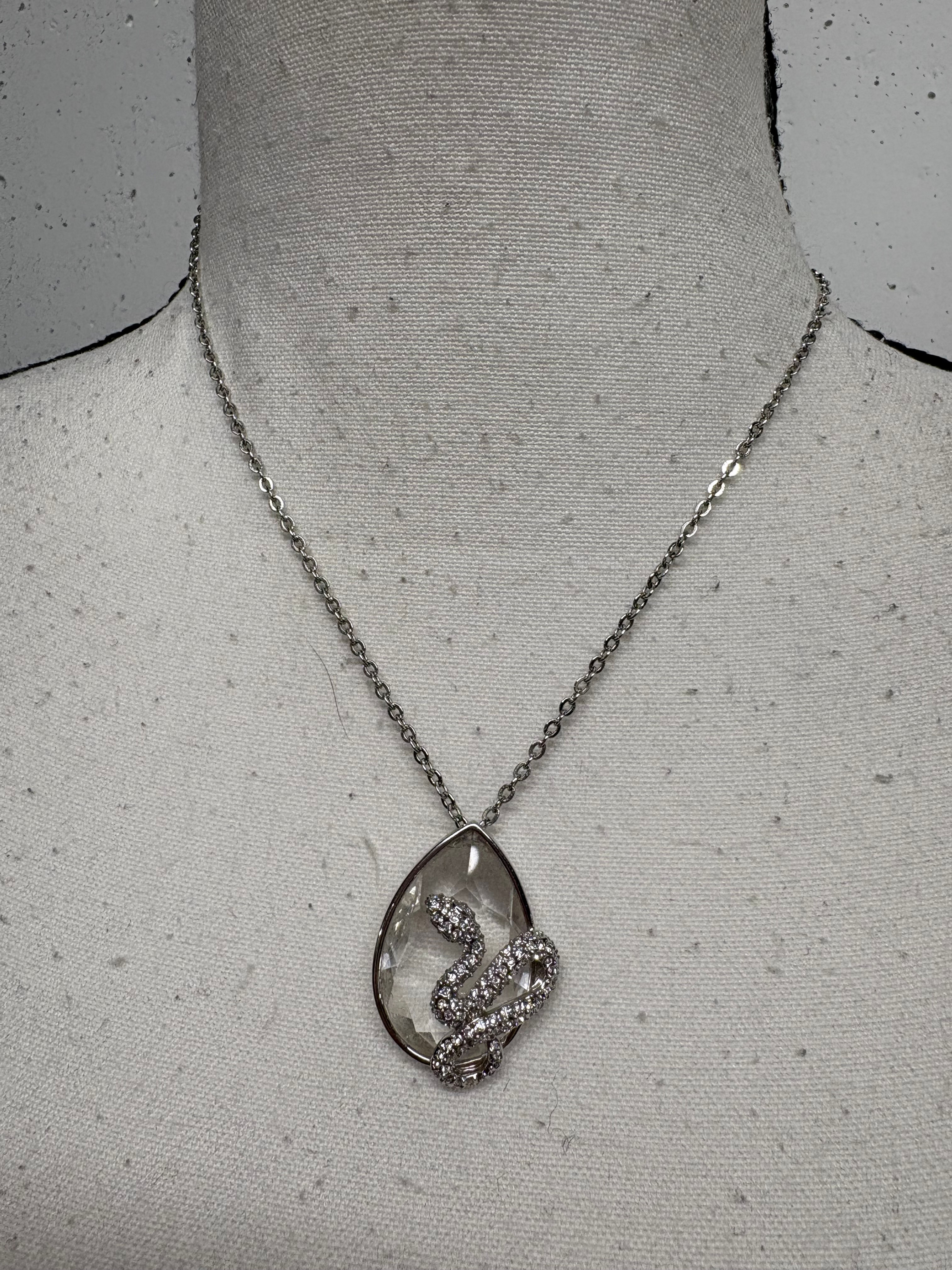 Silberne Kette mit Anhänger, Schlangendesign, auf einer Büste, Nahaufnahme.