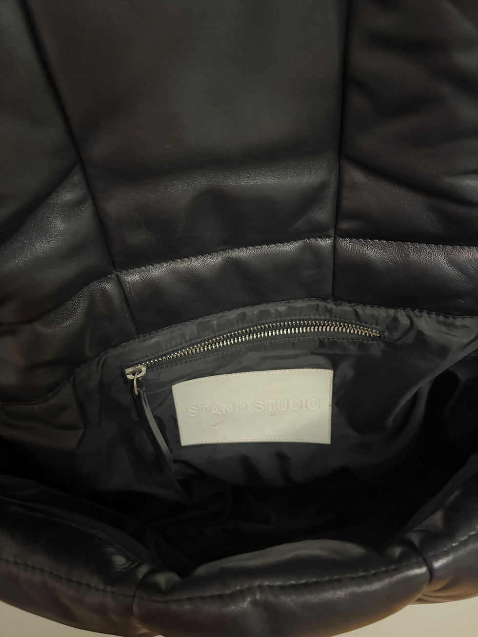 Miniaturbild: Schwarze Ledertasche mit leerem Etikett im Inneren, nah Detailansicht, Produktfotografie.