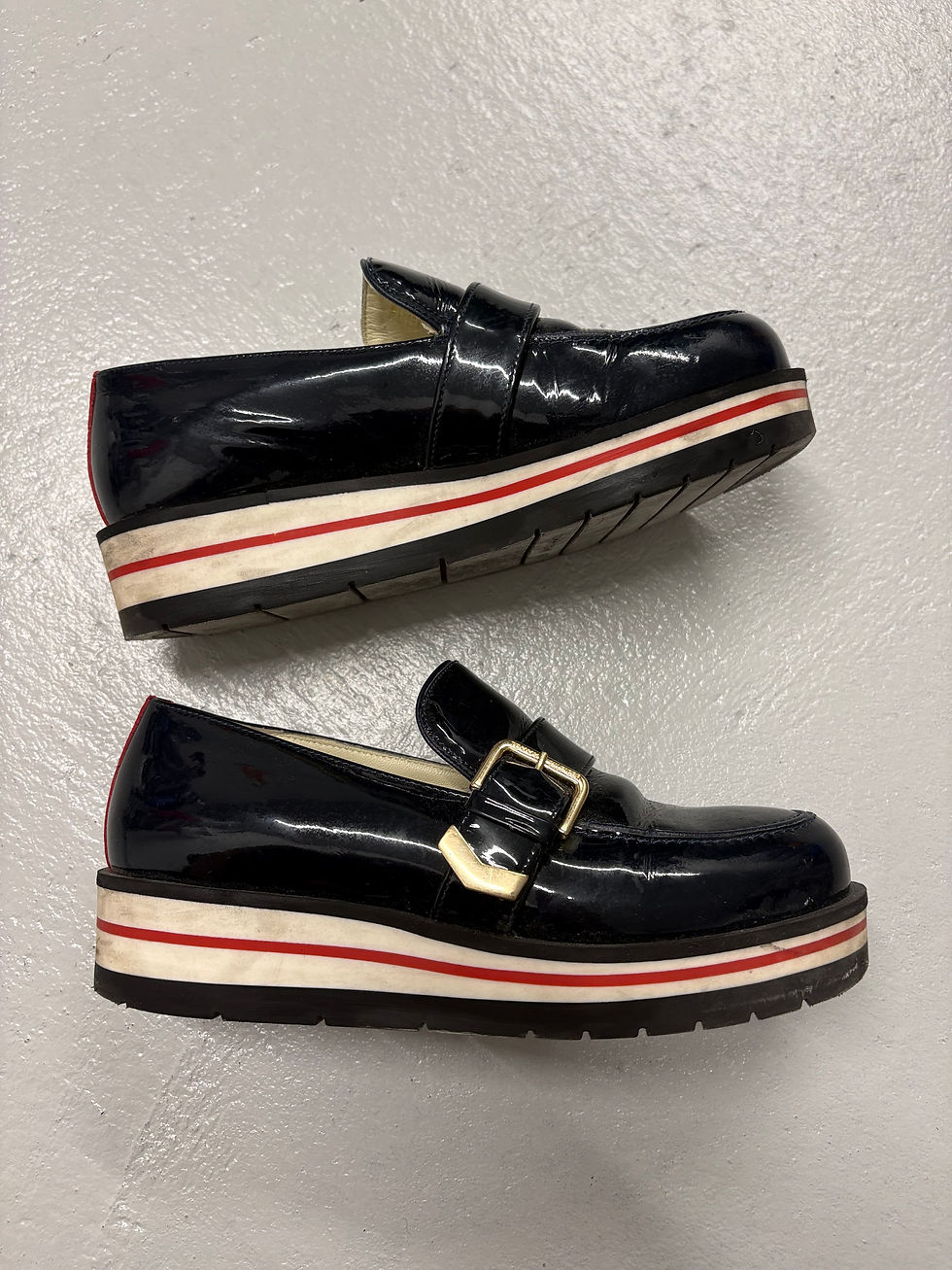 Miniaturbild: Schwarze Lacklederschuhe mit weiß-roter Sohle. Goldene Schnalle und Blockabsatz.