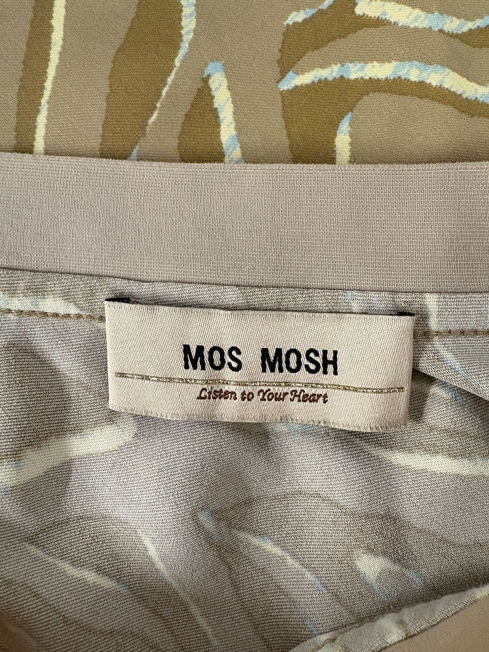 Miniaturbild: MOS MOSH Label Listen to Your Heart beige fabric background close-up shot.