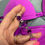 Miniaturbild: Hand holding a purple string with rhinestones, next to a purple bikini top.