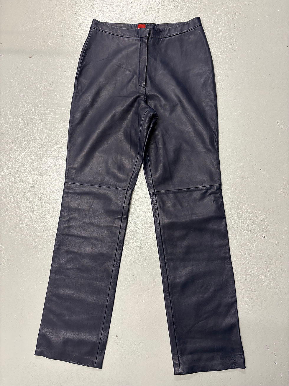 Dunkelblaue Lederhose auf weißem Untergrund, eng geschnitten, hochwertige Verarbeitung.